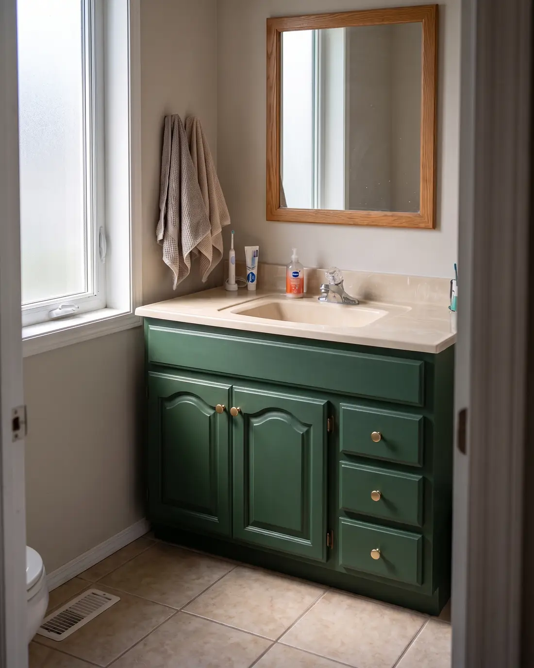 Bathroom vanity with raised-panel doors painted deep forest green and fitted with brushed gold knobs, concept render